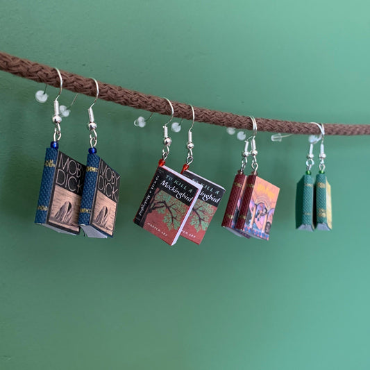 four mini book earrings hanging on a rope