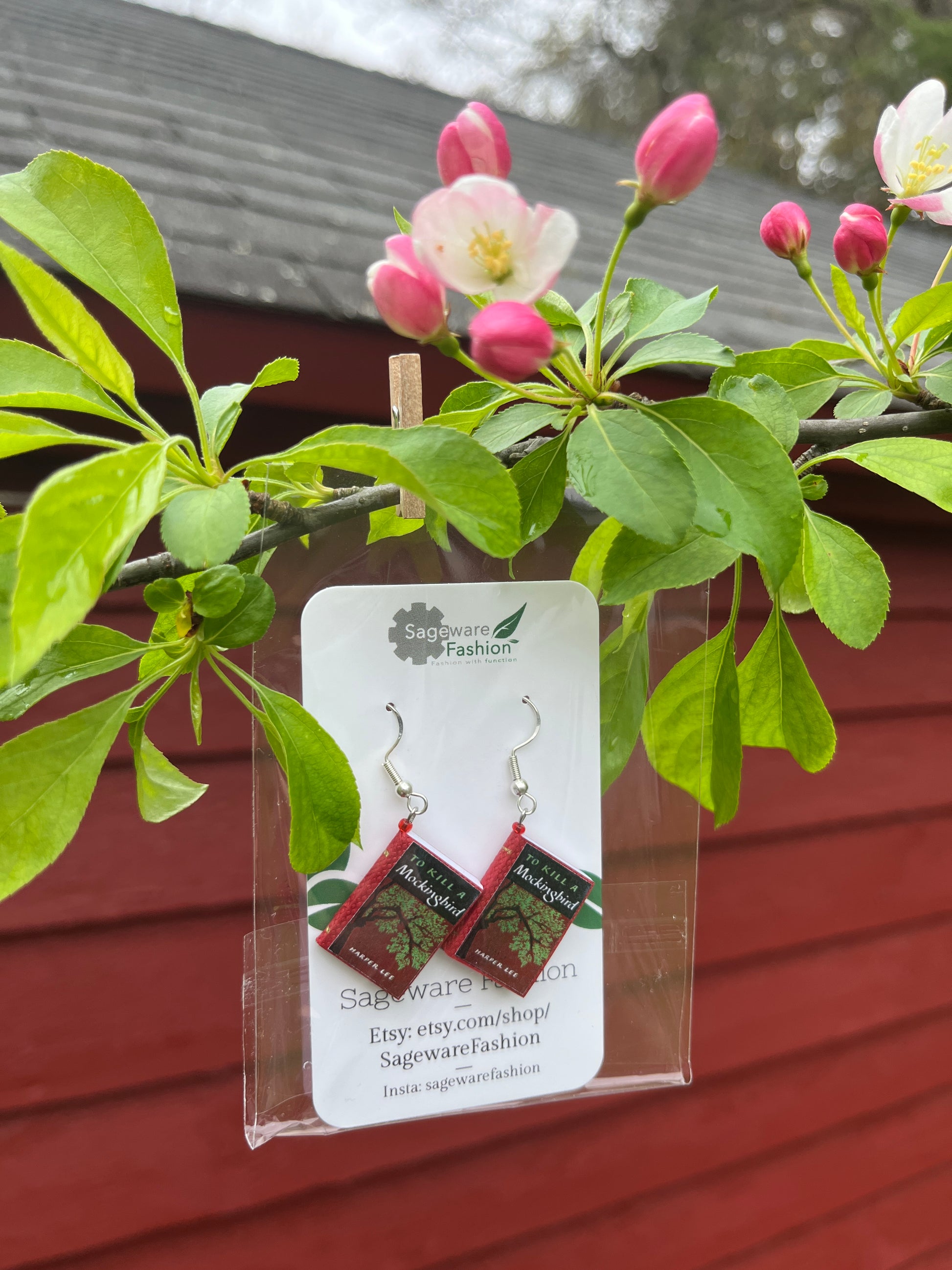 packaged red book earrings clipped to a tree branch